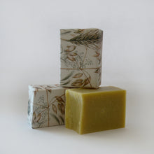 Load image into Gallery viewer, Three bars of soap. One yellow soap is unwrapped and two others have wrappers with images of oat plants 
